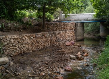 Gabion retaining walls along a natural stream at Babylonstoren Estate, showcasing hardscaping and erosion control work—Estate Gardens maintained by CSA Landscaping