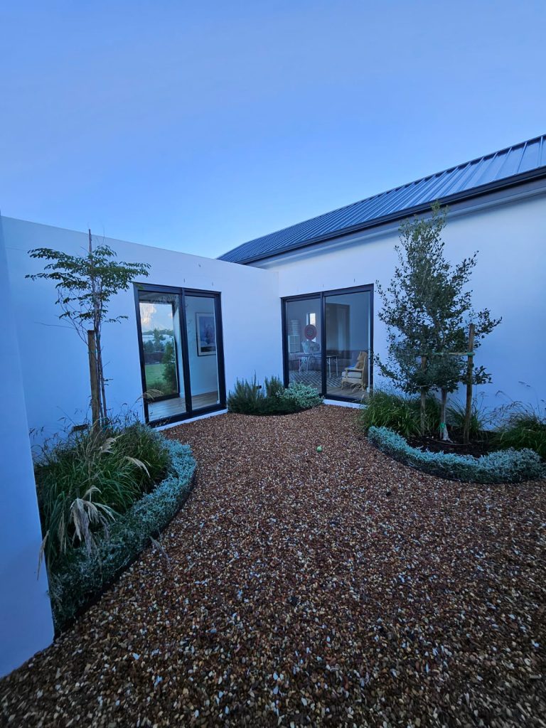 Internal gravel courtyard with young trees, silver foliage borders and ornamental grasses by CSA Landscaping, leading precision landscapers in the Boland and Cape Winelands, at The Acres at Pearl Valley