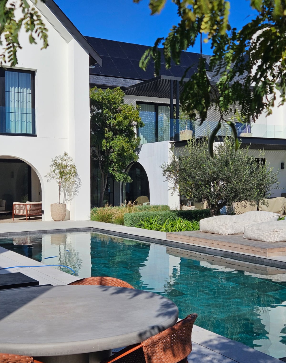 Poolside seating with mature olive trees and soft planting by CSA Landscaping, leading precision landscapers in the Boland and Cape Winelands, The Acres at Pearl Valley. CSA Landscaping
