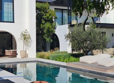 Poolside outdoor living area with mature olive trees (Olea europaea), soft planting and modern architecture by CSA Landscaping at The Acres at Pearl Valley, Paarl
