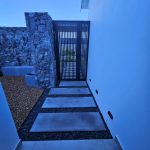 Entrance pathway with stone cladding and stepping stones by CSA Landscaping at a contemporary home in The Acres at Pearl Valley