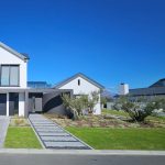 Street view of a contemporary home with multi-stem olive trees, clean lawn and stepping-stone pathway by CSA Landscaping, the best in Boland and Cape Winelands landscaping, at Val de Vie Estate