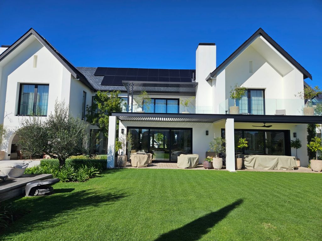 Rear lawn and covered outdoor living area with olive trees, agapanthus and potted citrus at a Val de Vie residence, Paarl, by CSA Landscaping, best landscapers in the Boland and Cape Winelands