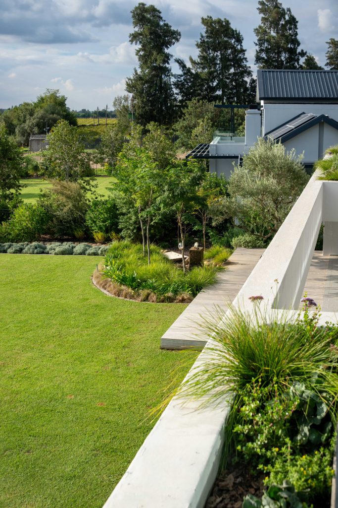 View from the balcony planter down to lawn, timber boardwalk, Dietes and granite water feature at Val de Vie Estate, Paarl, by CSA Landscaping — leading landscapers in the Boland and Cape Winelands