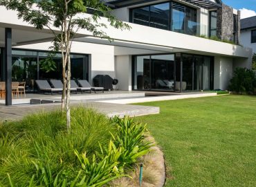 Curved lawn-edge bed of Dietes and ornamental grasses with a feature tree beside the outdoor terrace at Val de Vie Estate, Paarl, by CSA Landscaping — leading landscapers in the Boland and Cape Winelands
