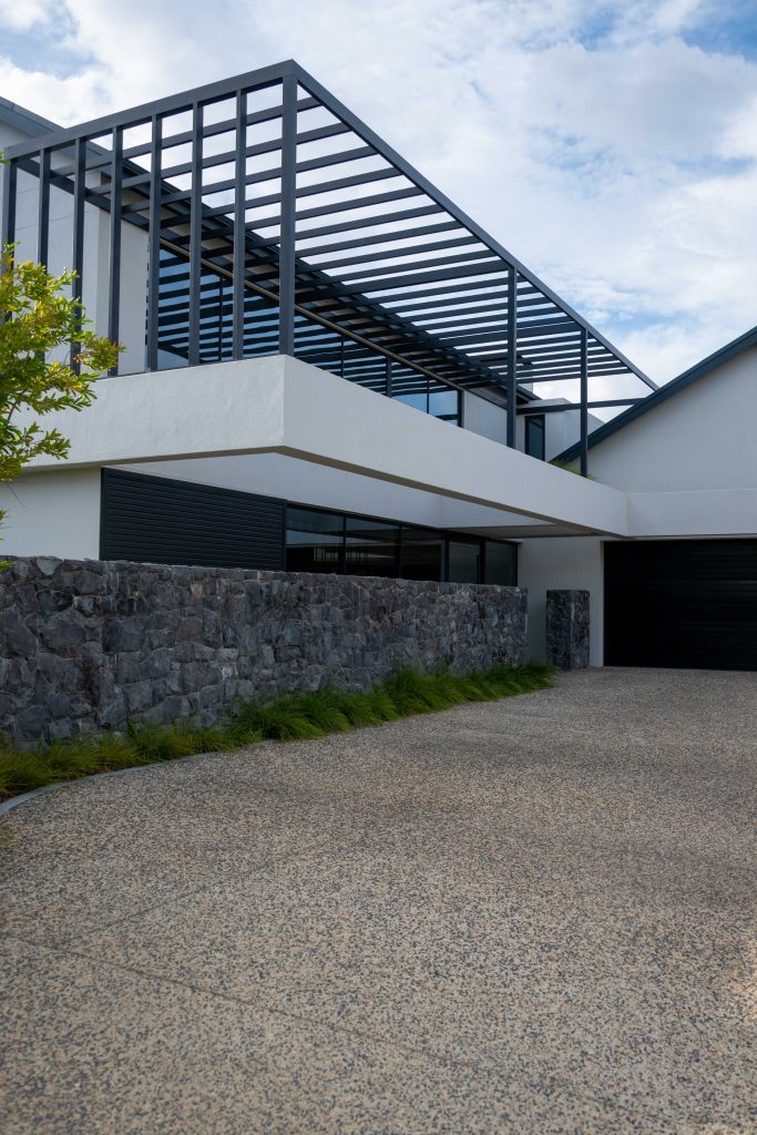 Stone retaining wall with ornamental grasses and a feature tree beside the driveway at Val de Vie Estate, Paarl, by CSA Landscaping — leading landscapers in the Boland and Cape Winelands