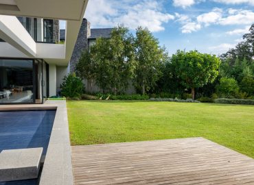 Timber deck and pool terrace opening onto lawn and layered garden beds at a contemporary home in Val de Vie Estate, Paarl, by CSA Landscaping — leading landscapers in the Boland and Cape Winelands