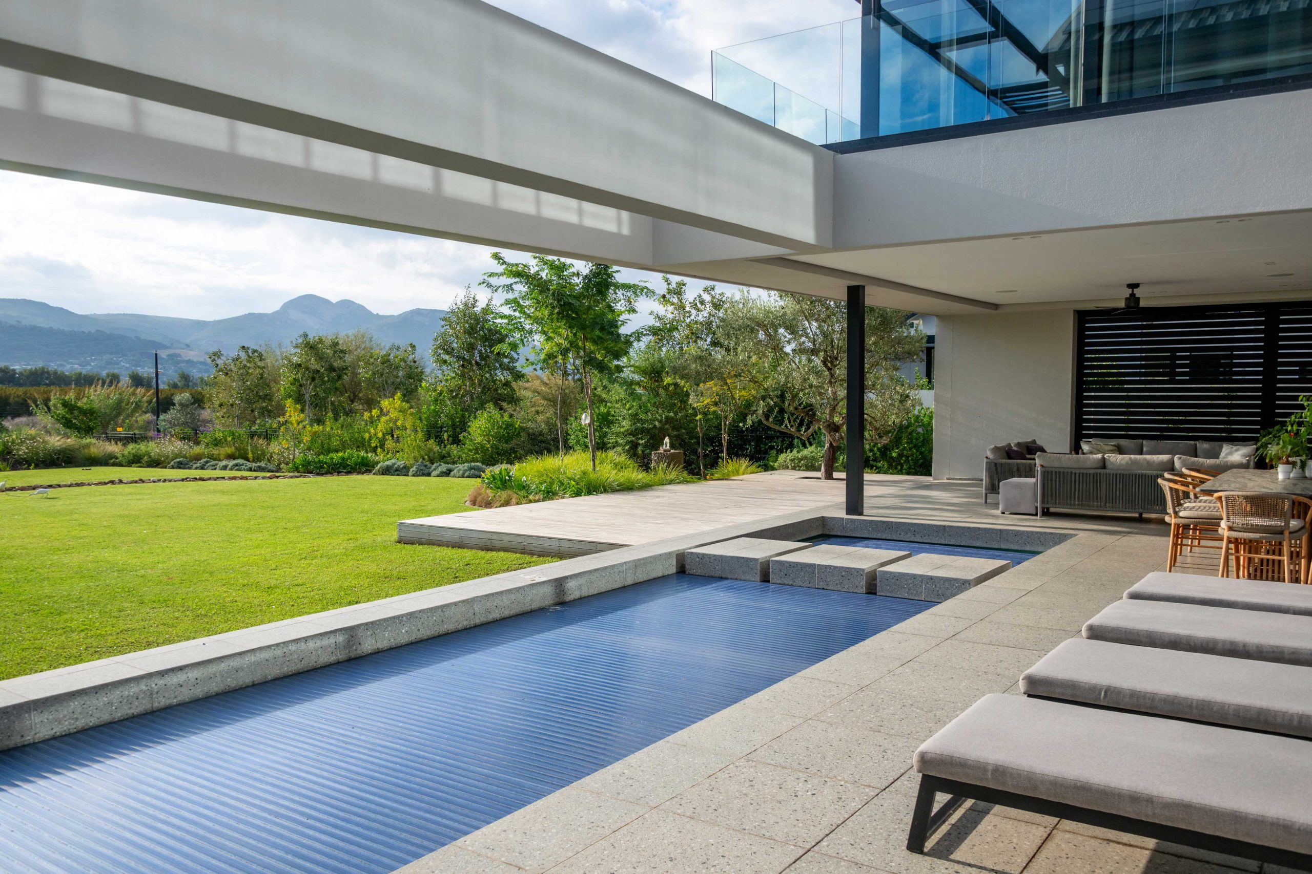 Pool stepping blocks looking through to olive trees, ornamental grasses and the garden at Val de Vie Estate, Paarl, by CSA Landscaping — leading landscapers in the Boland and Cape Winelands