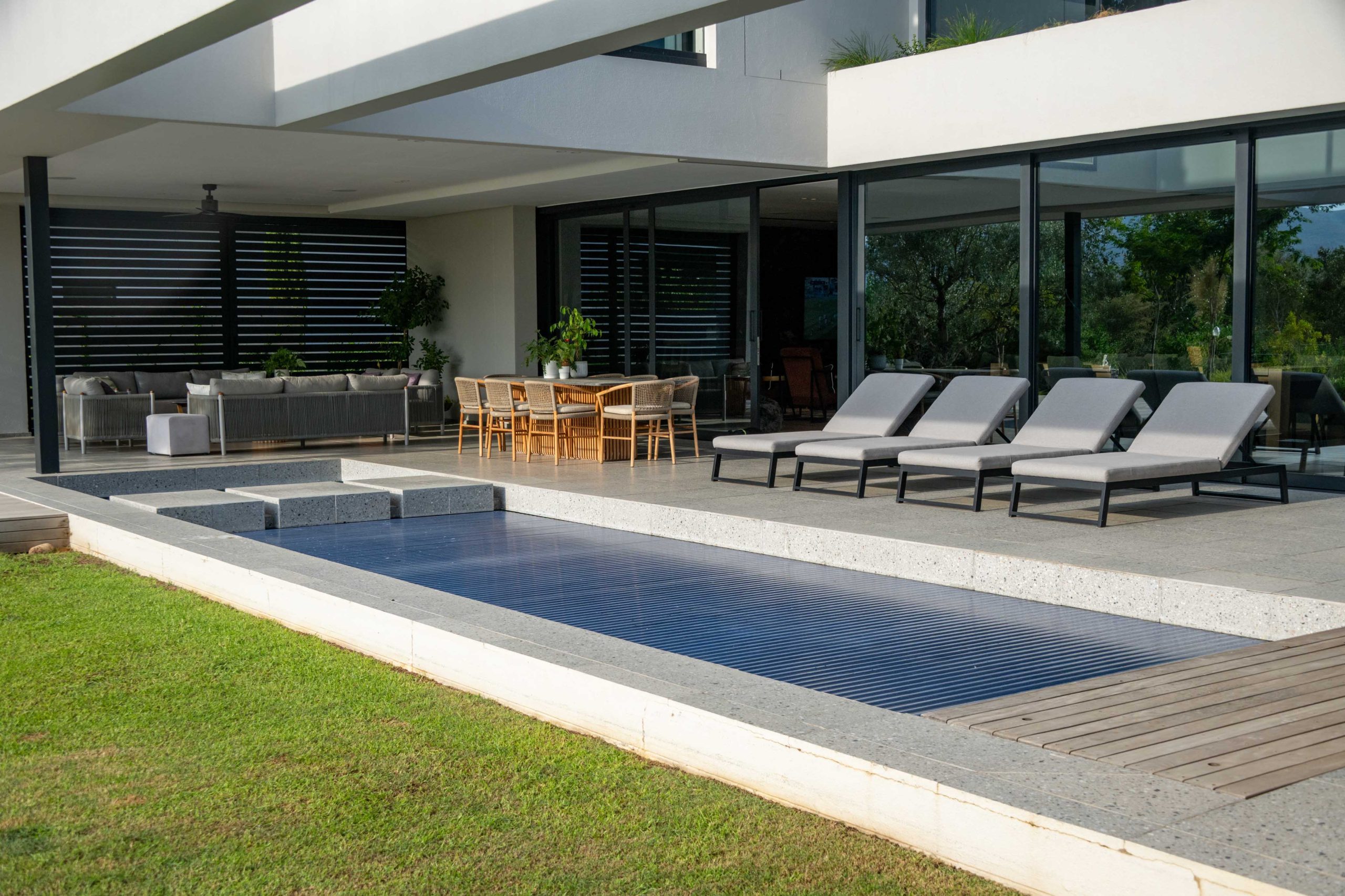 Covered pool terrace with granite stepping blocks and timber deck opening onto the lawn at Val de Vie Estate, Paarl, by CSA Landscaping — leading landscapers in the Boland and Cape Winelands