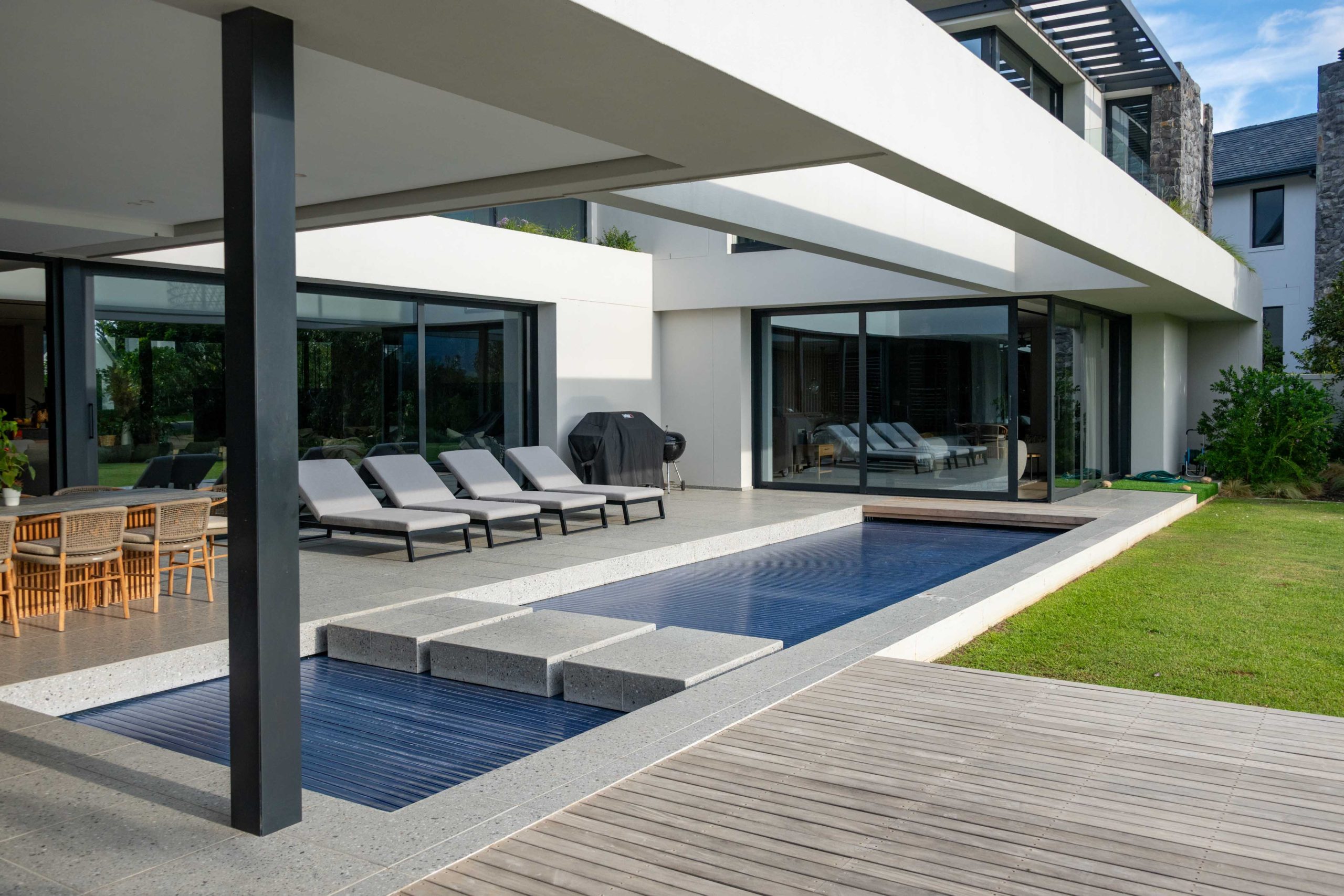 Pool and outdoor living terrace flowing into the lawn garden at a contemporary home in Val de Vie Estate, Paarl, by CSA Landscaping — leading landscapers in the Boland and Cape Winelands