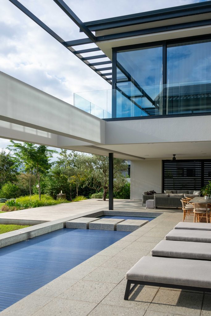 Pool terrace opening onto lawn, olive trees and mountain views at Val de Vie Estate, Paarl, by CSA Landscaping — leading landscapers in the Boland and Cape Winelands